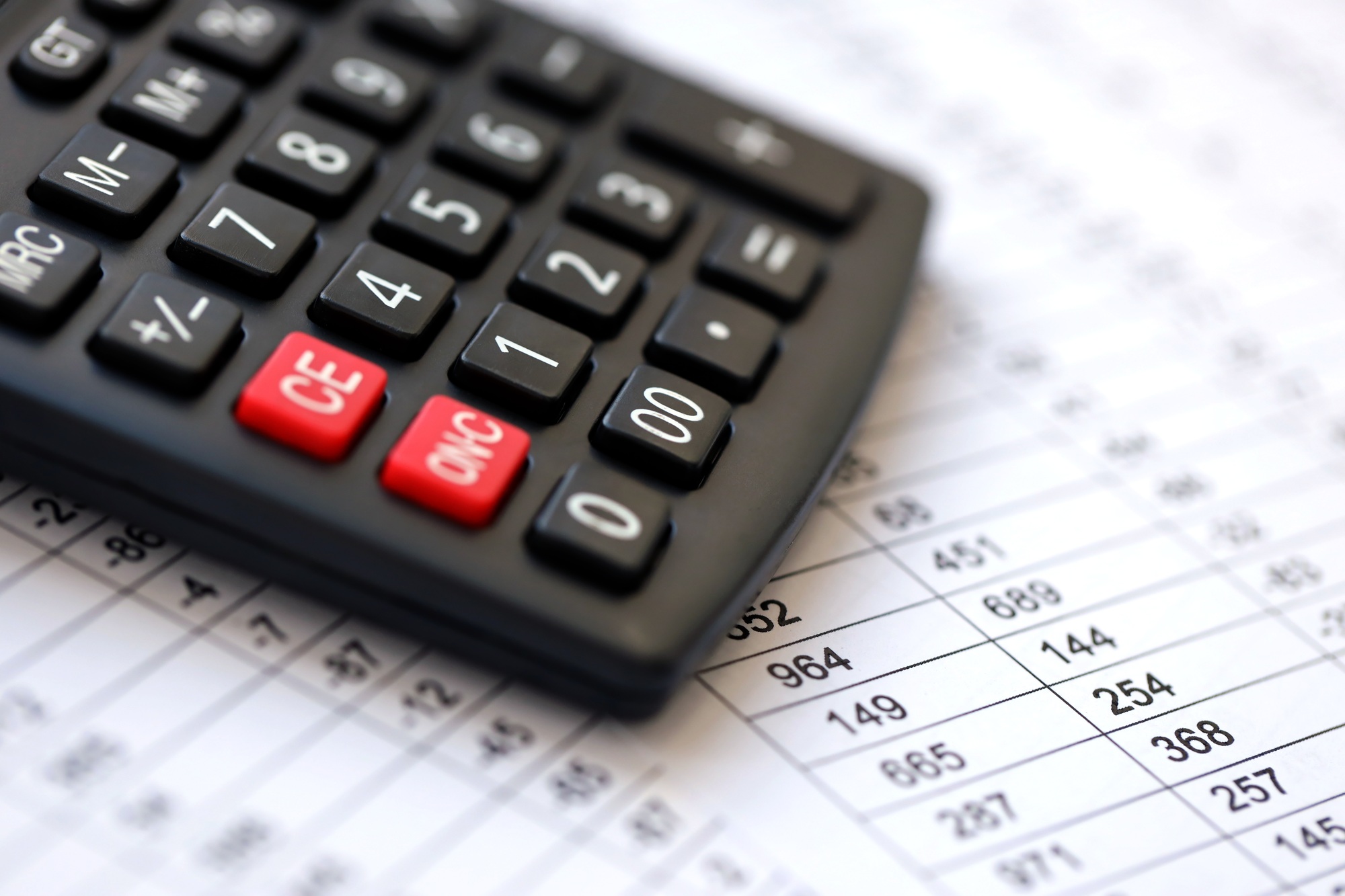 Big black calculator lies on financial statement and balance sheeet on desk of auditor