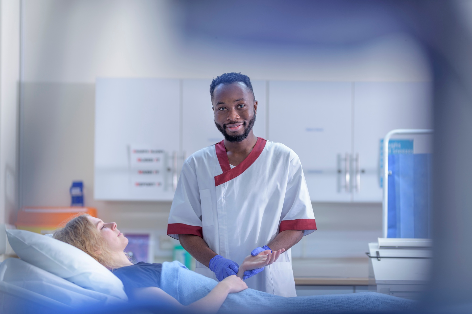 Portrait of male nurse with patient in hospital ward