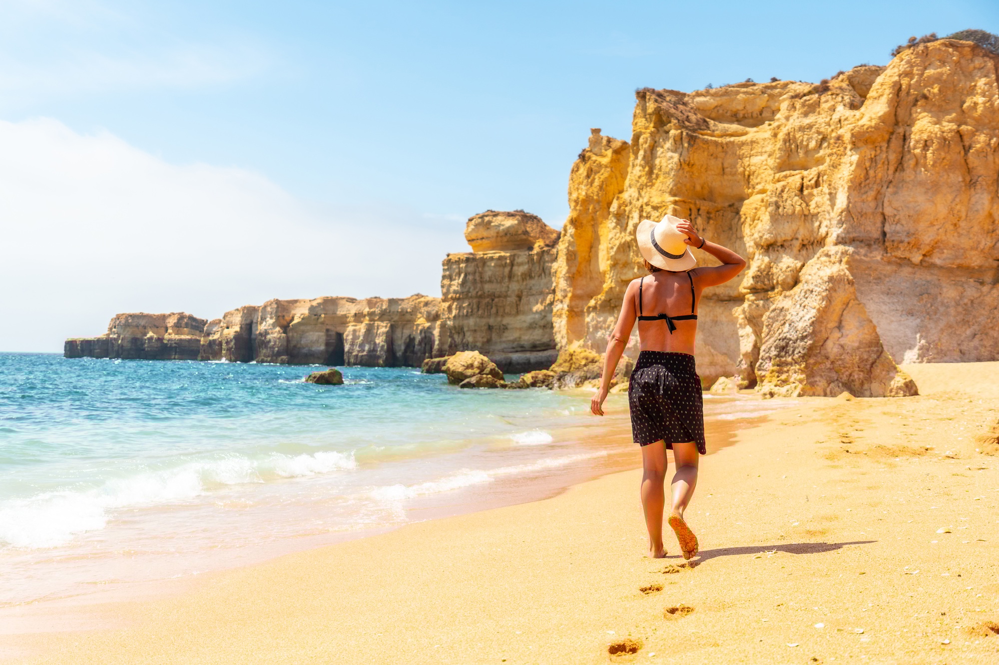 A woman with a hat on a beach holiday at Praia da Coelha, Algarve, Albufeira. Portugal